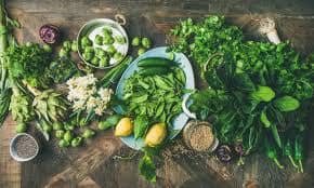 green vegetables and two lemons on plates on a wooden table