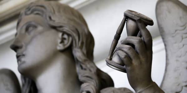 Statue of winged woman holding hourglass in her hand