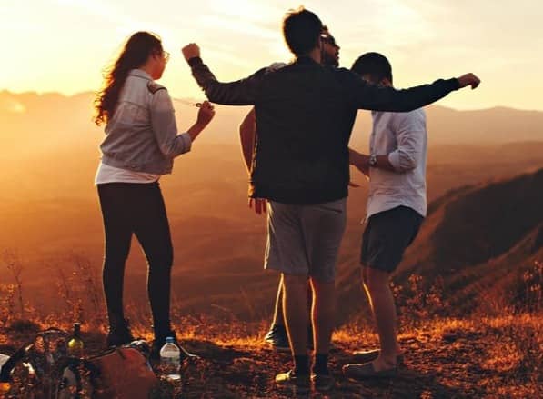 four people standing on edge of mountain