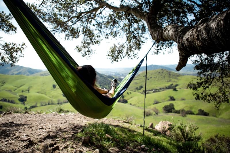 woman in a green hammock looking out over the hills