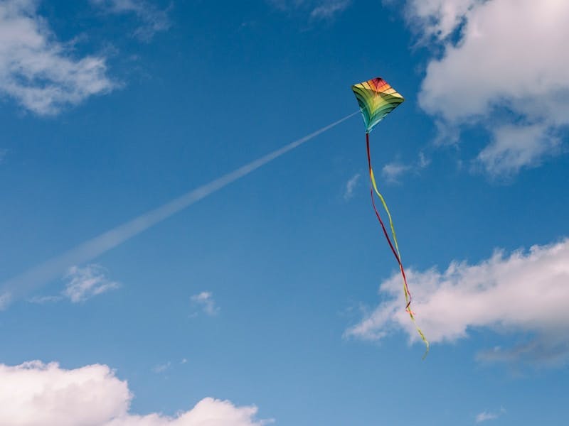 multi colored kite flying in a blue sky