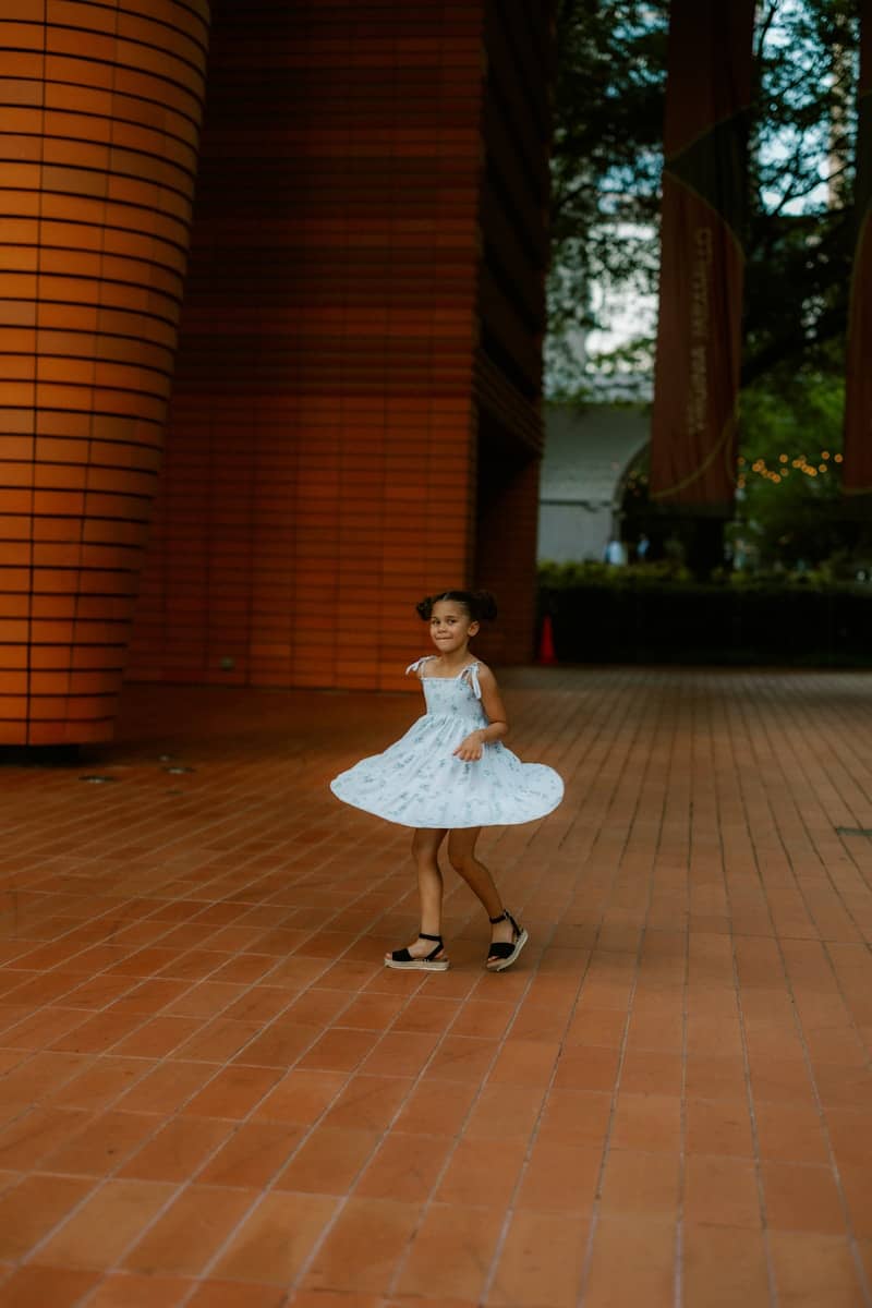 A young girl spins in a whimsical dress.