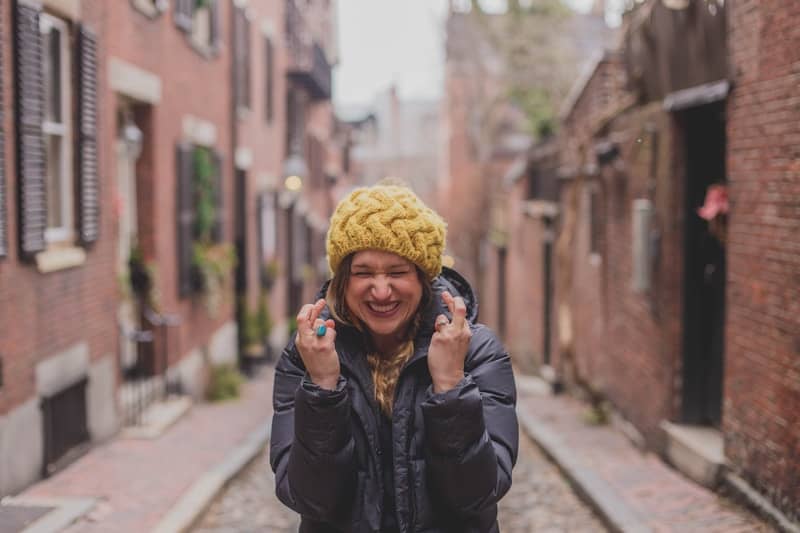 girl in a yellow beanie crossing fingers on both hands for good luck