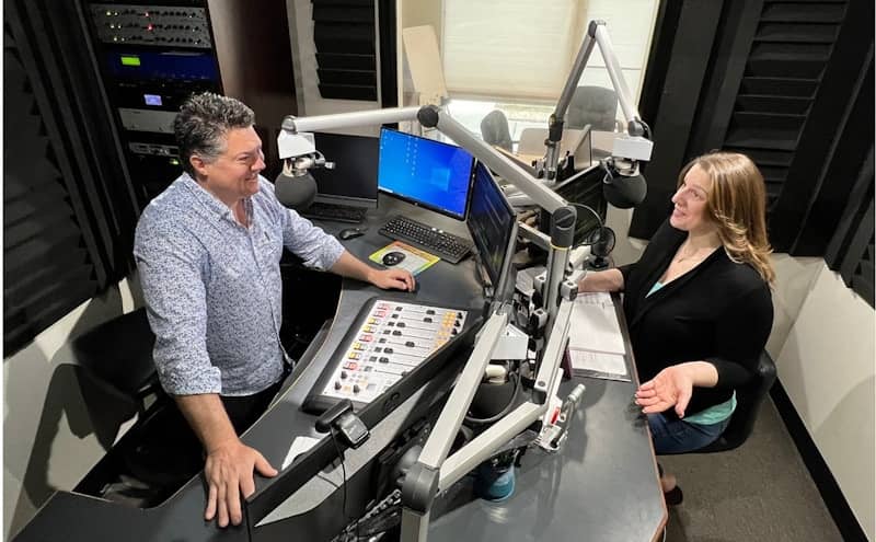 Man and woman talking in a professional radio studio.