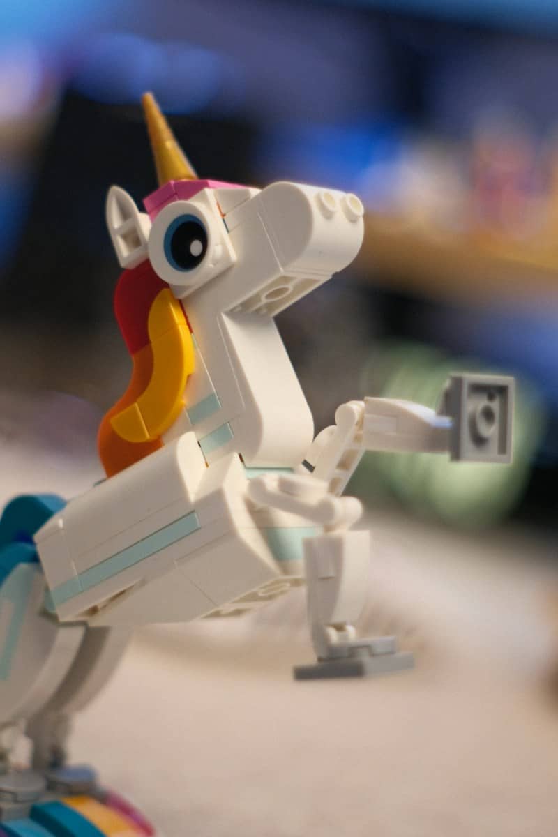 A white lego unicorn with a colorful mane rearing up