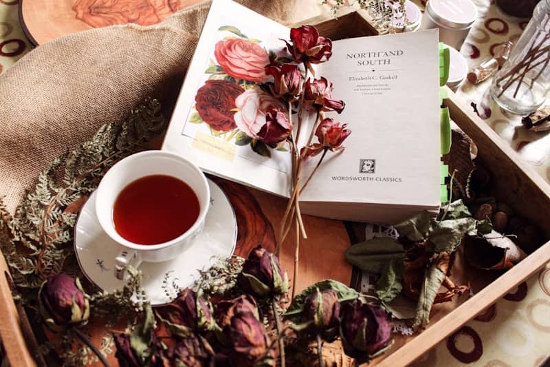 A cup of tea with dried flowers and a book.