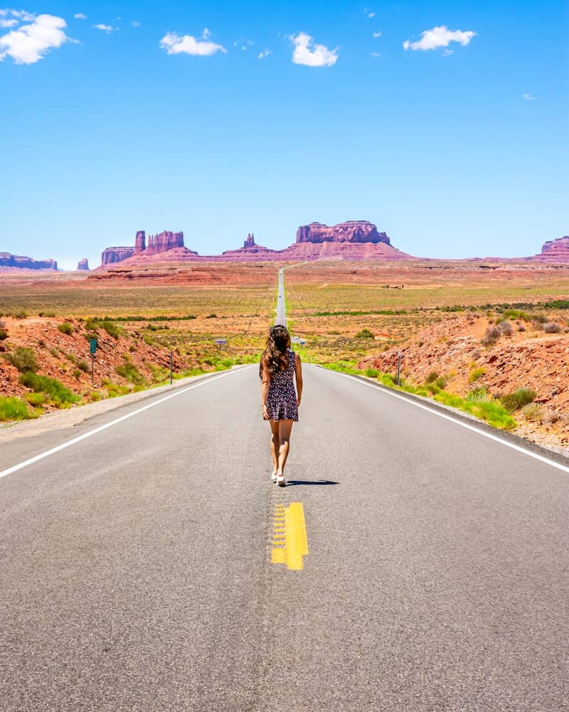 woman in black and grey dress walking in middle of highway