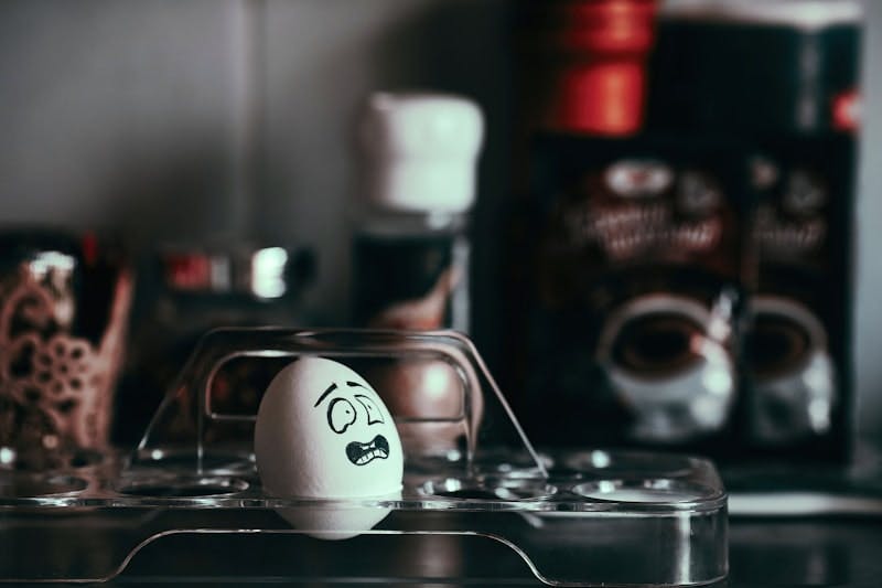 A chicken egg with a drawn emotional egg expressing horror and frustration. Blurred background, emotion, post-traumatic syndrome
