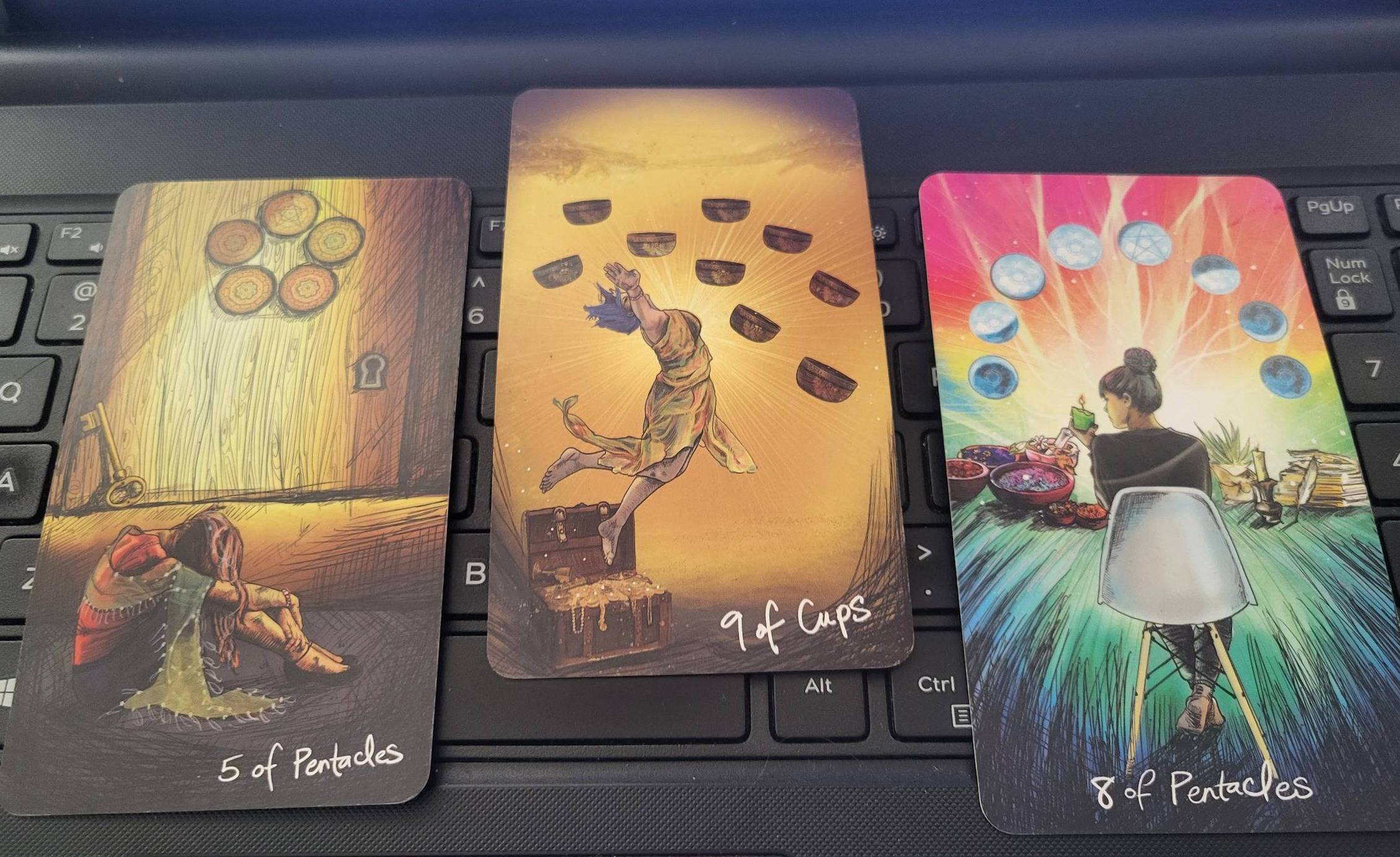 Tarot spread with the 5 of Pentacles, 9 of Cups, and 8 of Pentacles