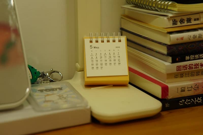 A small desk calendar sits beside a stack of books.