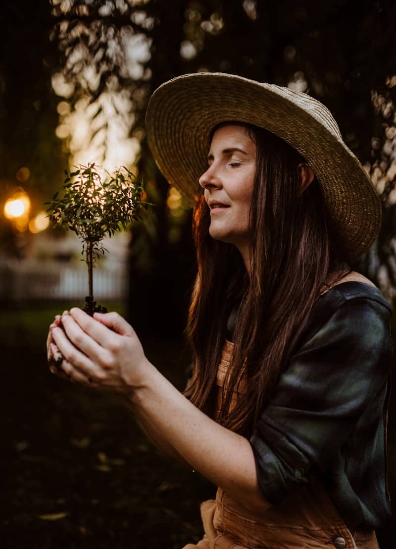 A woman in a hat holding a small plant