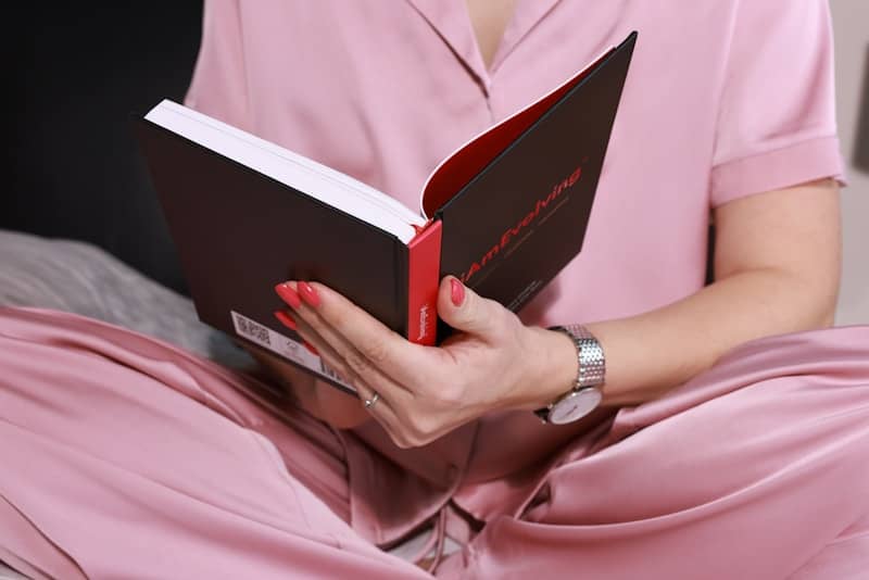 Woman in pink pajamas reading a book