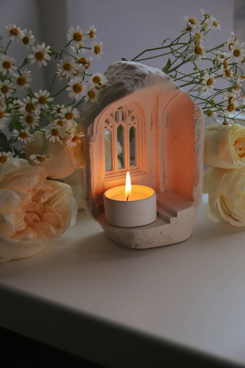 Lit candle in a decorative gothic architectural holder.