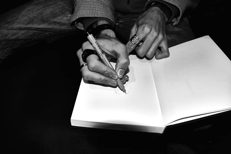 Hands writing in a blank book with a pen