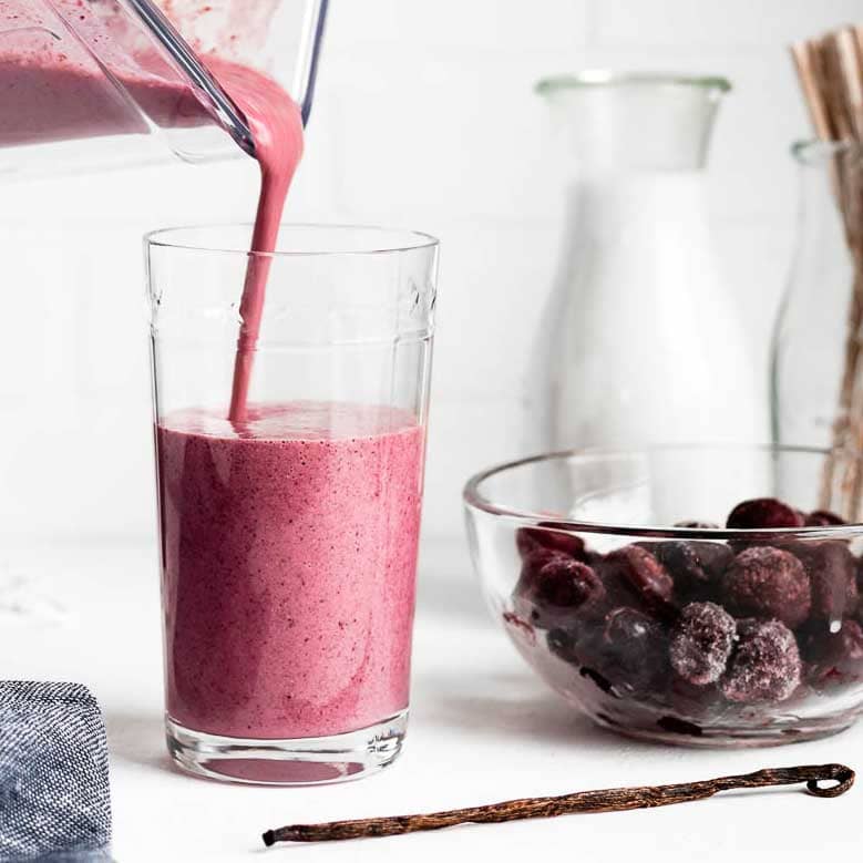 pouring pink smoothie into a glass