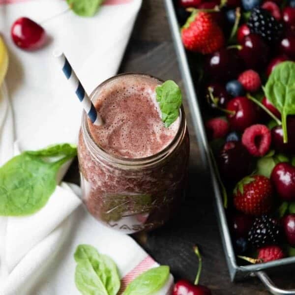 mason jar with smoothie surrounded by berries