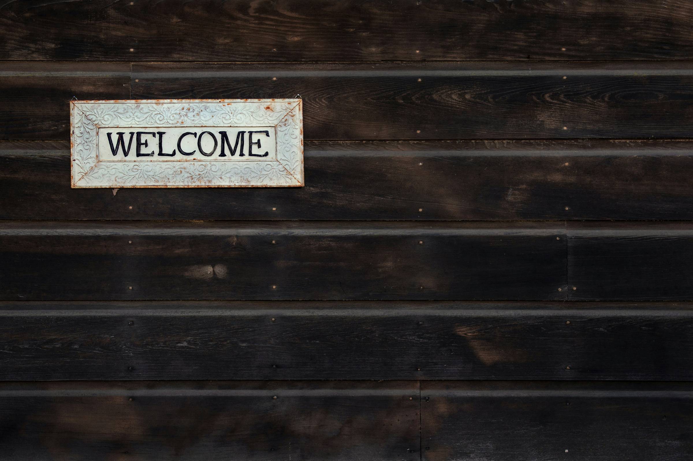 A welcome sign. Photo by <a href="https://unsplash.com/@timmossholder?utm_content=creditCopyText&utm_medium=referral&utm_source=unsplash">Tim Mossholder</a> on <a href="https://unsplash.com/photos/black-and-white-wooden-board-fwqB5mJNOcE?utm_content=credi