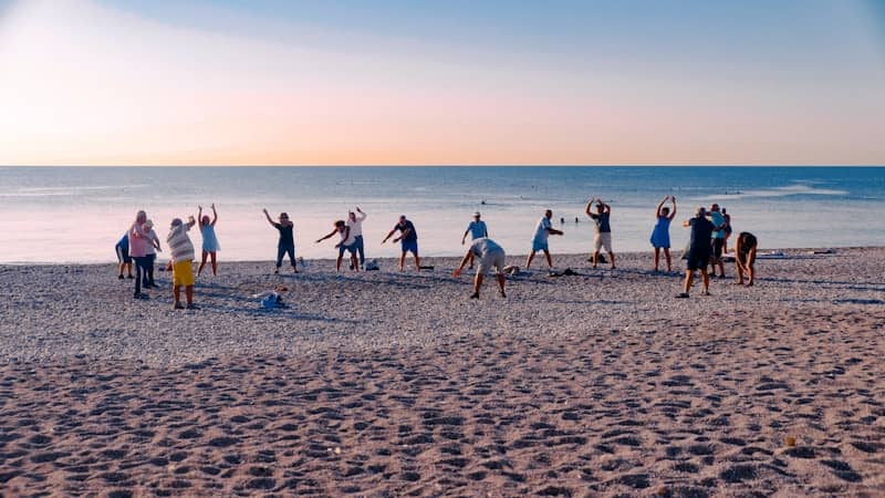 Group of people exercising on a sandy beach at sunset