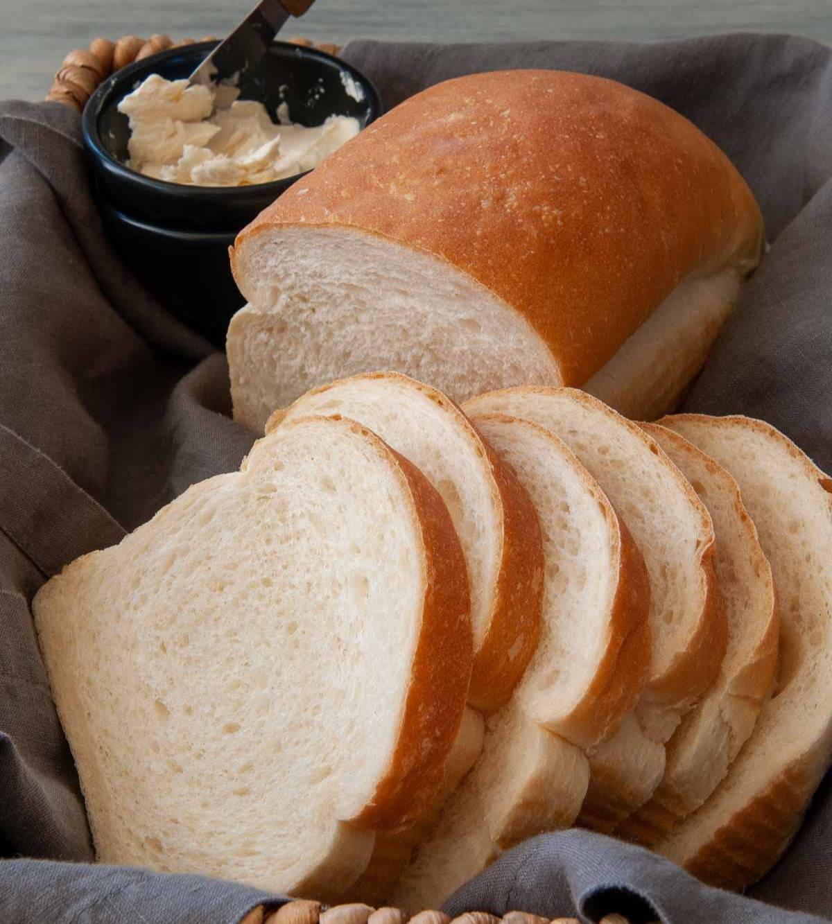 Sliced white bread in a basket with butter on the side