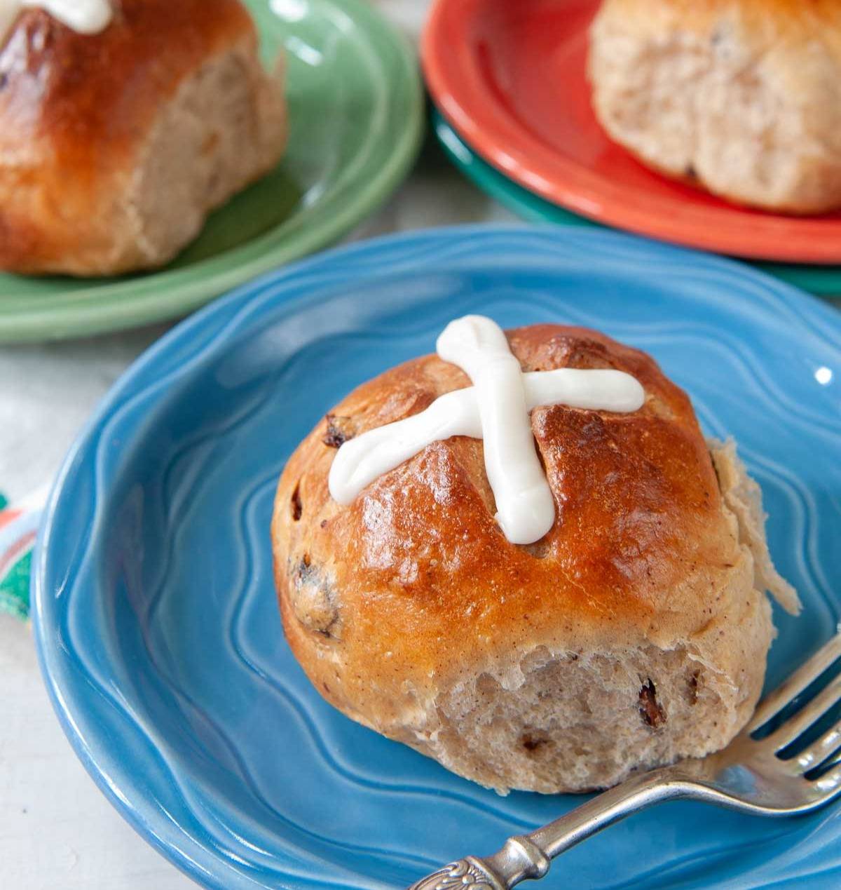 hot cross buns on brightly colored plates.