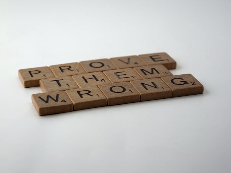 brown wooden blocks on white table that spell prove them wrong