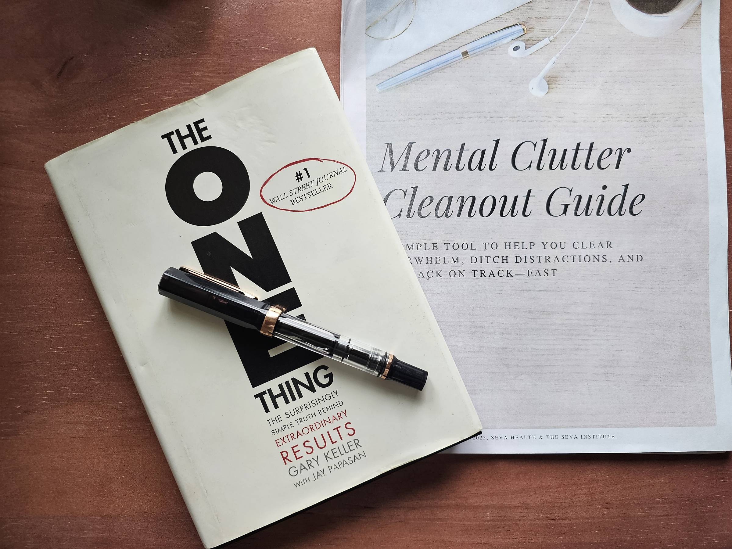 Gary Keller’s book 'The One Thing' paired with the Mental Clutter Cleanout Guide worksheets on a cozy desk, showcasing a system for turning mental overwhelm into clarity.