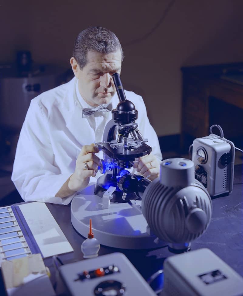 a man looking through a microscope at something