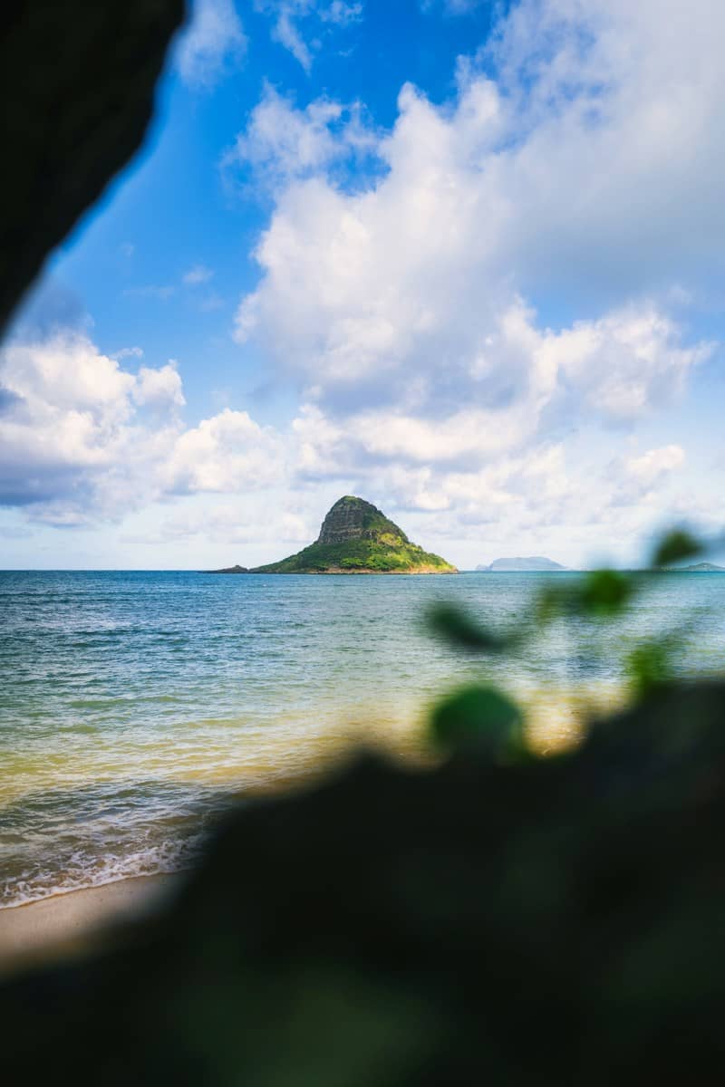 Island surrounded by ocean under a cloudy sky.