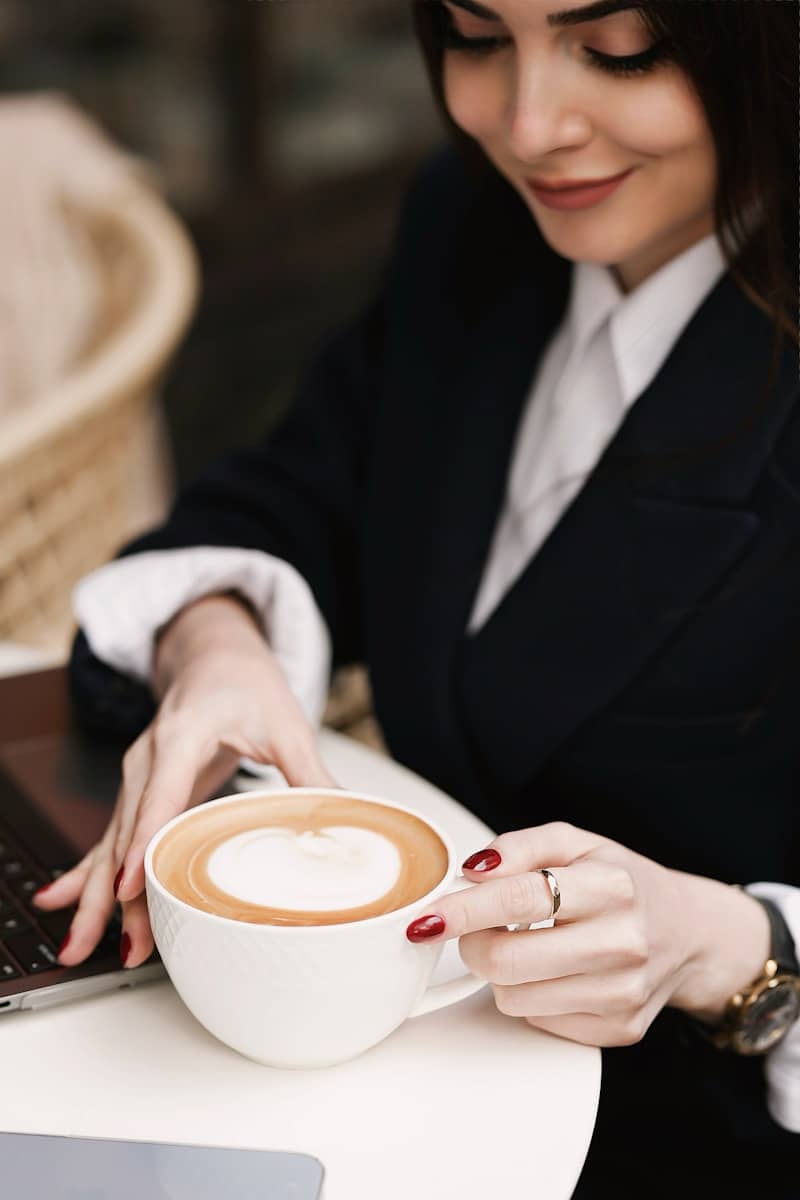 a woman sitting at a table with a laptop and a cup of coffee
