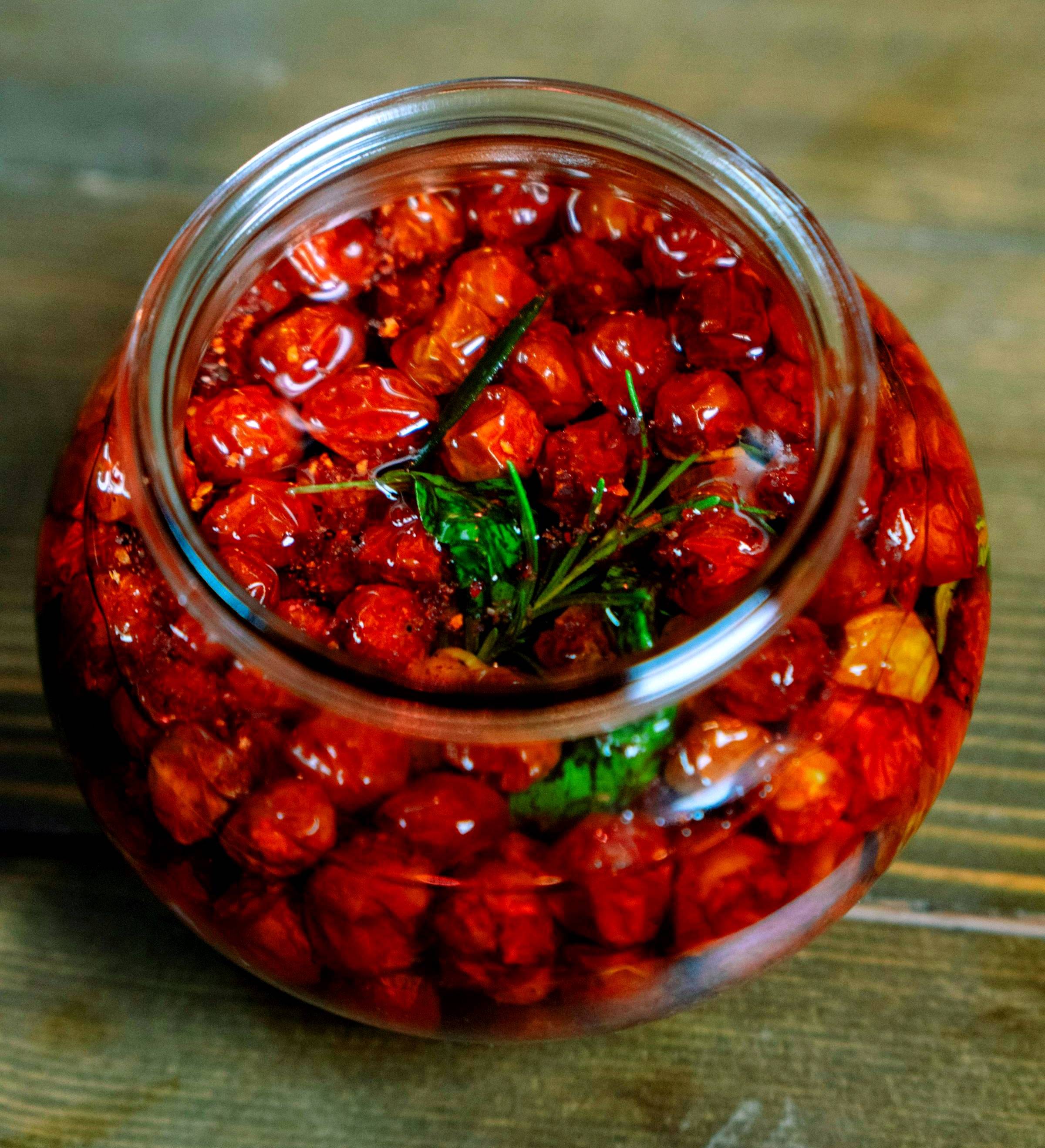 Homemade sunblush tomatoes in olive oil in a glass jar, ready to use in salads, pasta and antipasti.