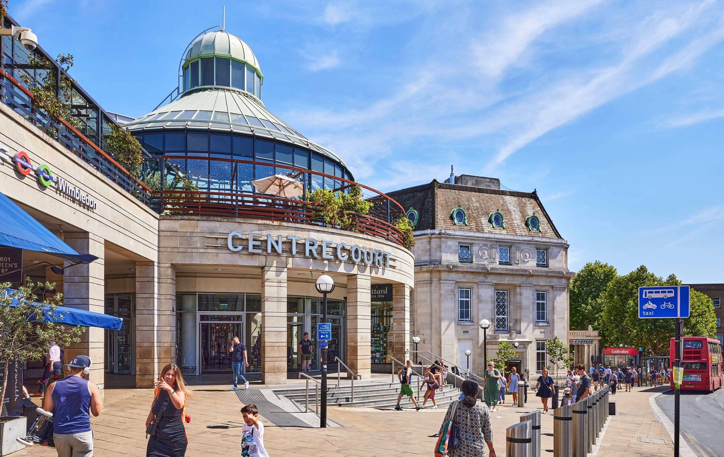 Wimbledon town centre with Centre Court shopping area, station signs, pedestrians and local transport links