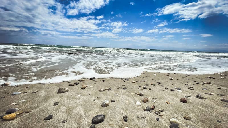 Sandy beach with ocean waves and a blue sky.