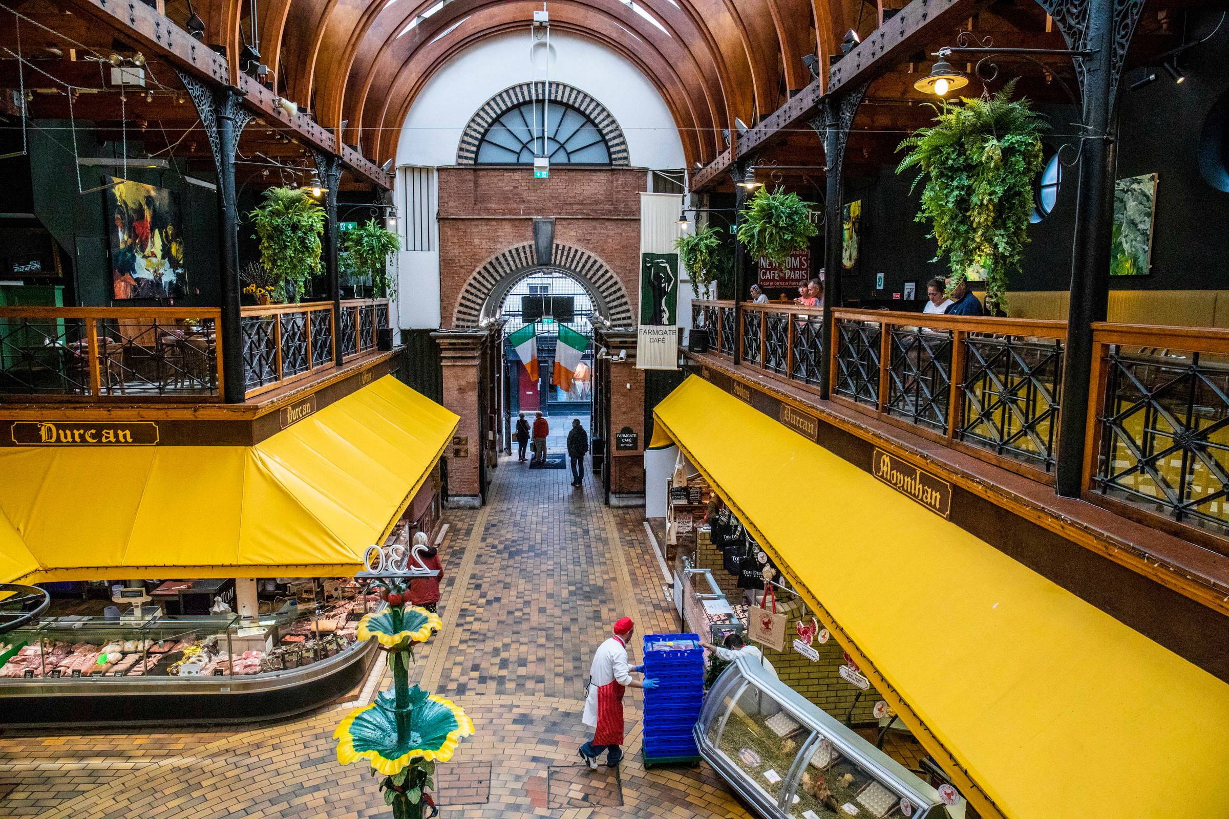 Interior of Cork’s English Market, showing the central aisle, yellow market awnings, upper gallery and Farmgate Café.