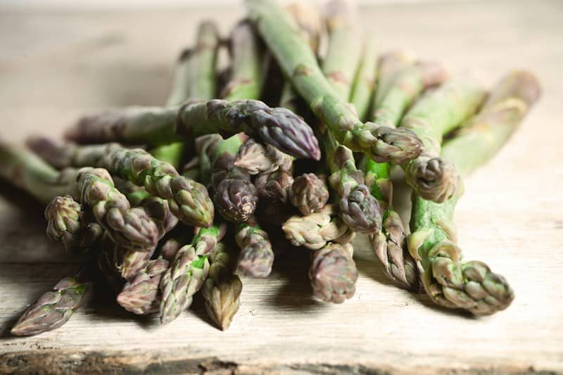 A pile of asparagus sitting on top of a wooden table