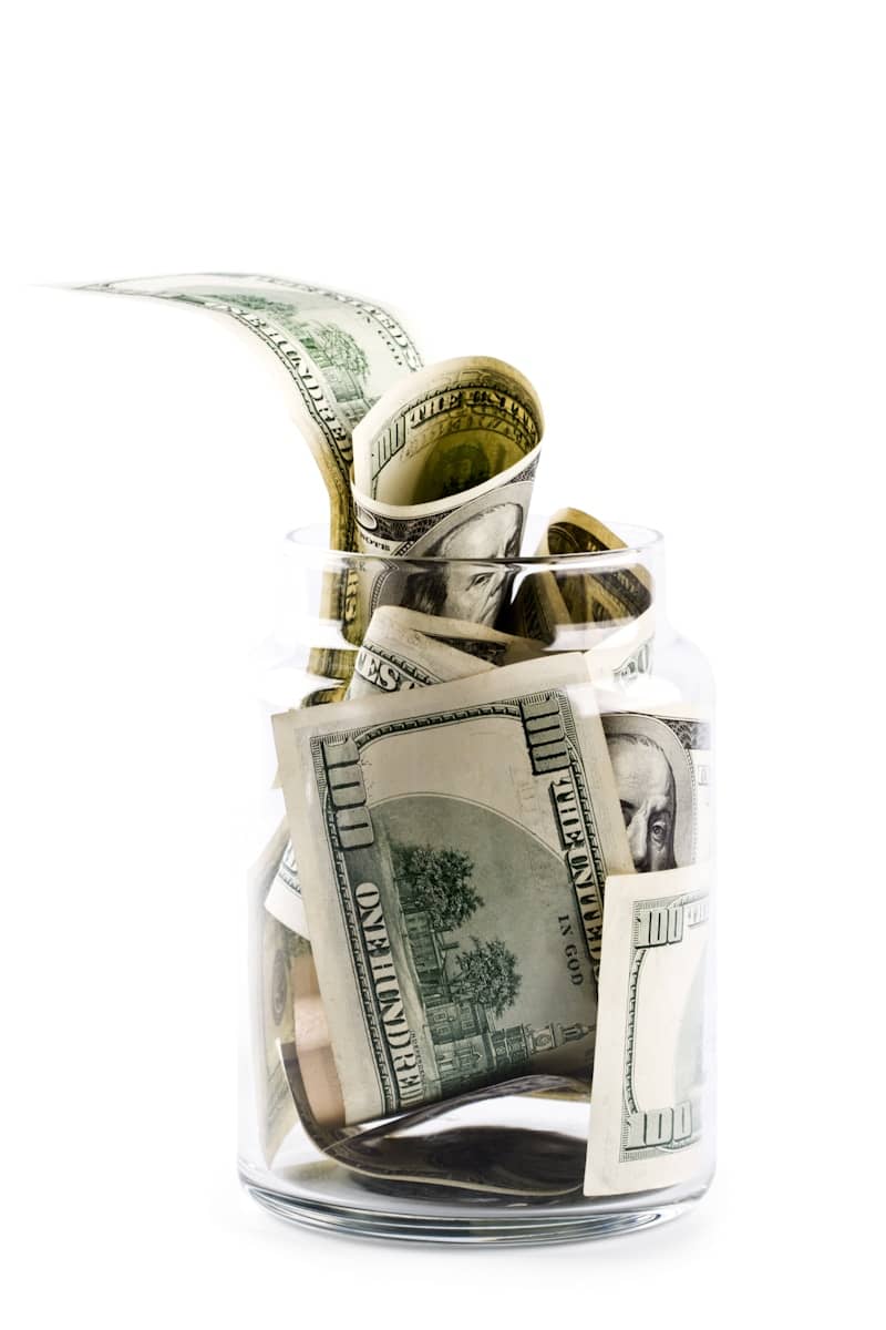 A glass jar filled with money on top of a table