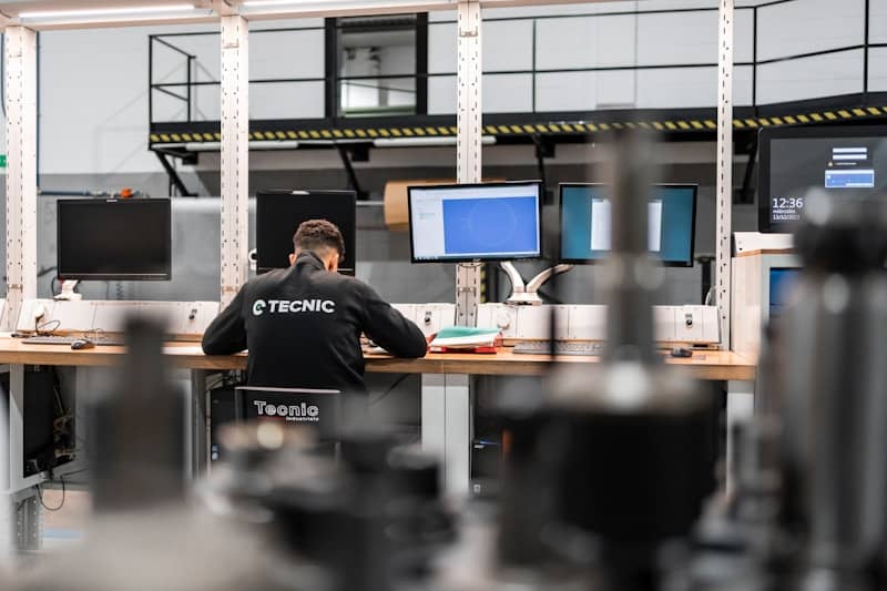 A worker is concentrating at multiple computer screens.