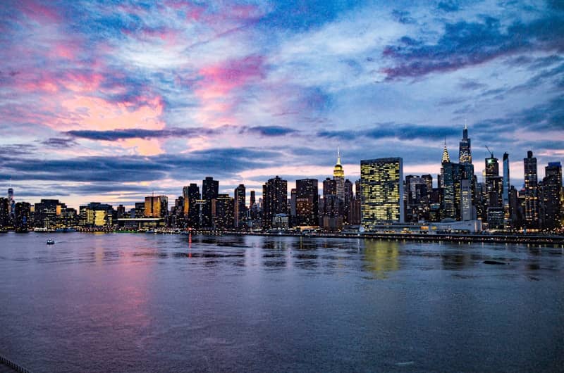 New york city skyline at dusk reflecting in water.