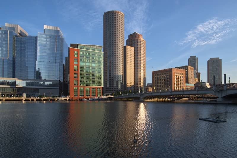 Modern cityscape with skyscrapers reflecting on water.
