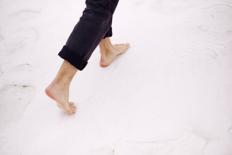 Barefoot person walking on a white surface.