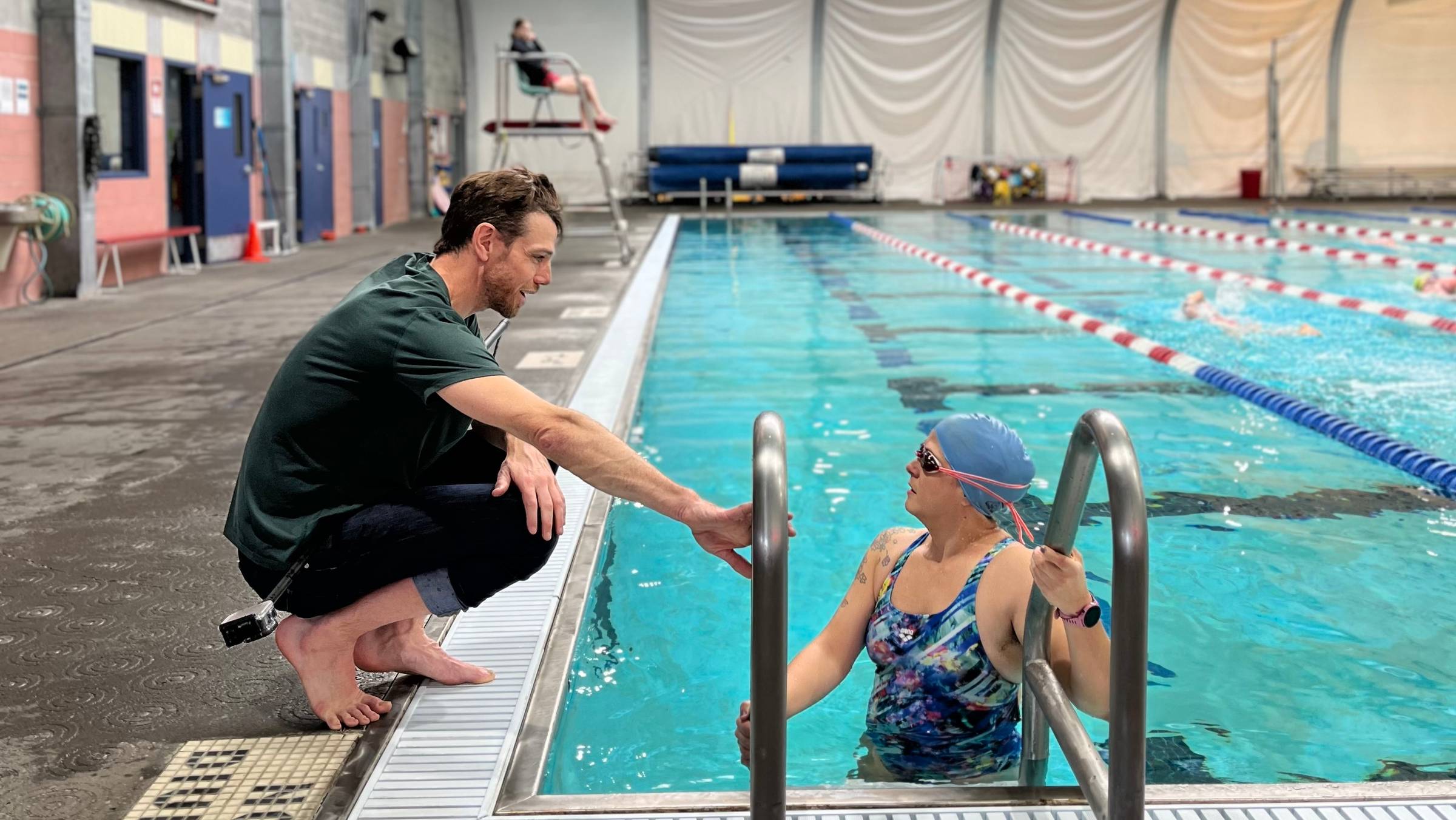 A picture of a swim coach talking to a swimmer in the pool