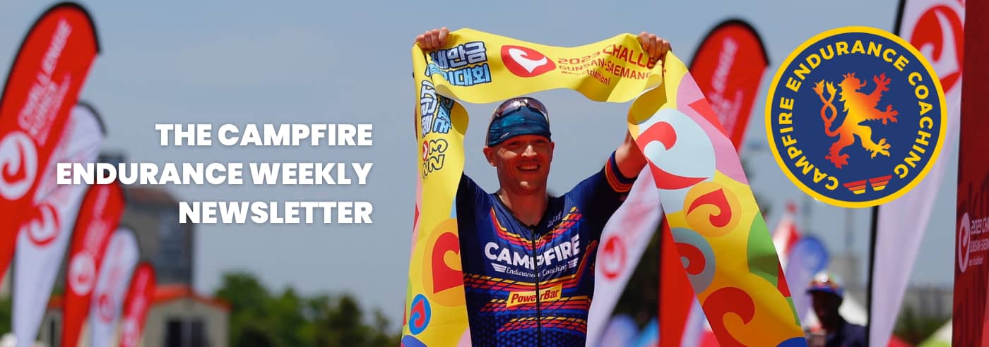 A picture of a triathlete crossing a finish line holding the finish tape aloft