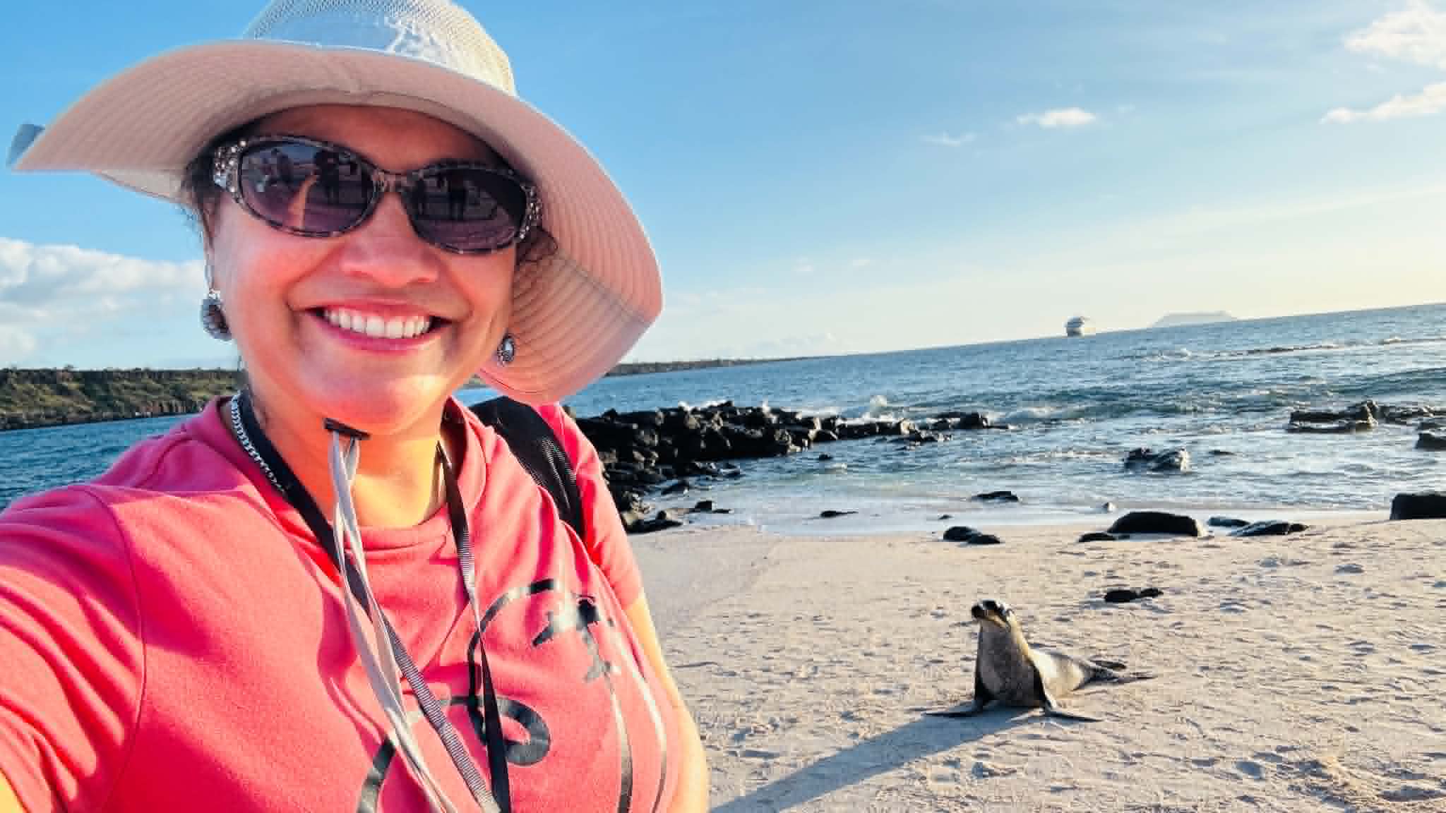 Sheyla in the Galápagos Islands taking a photo with a sea lion.