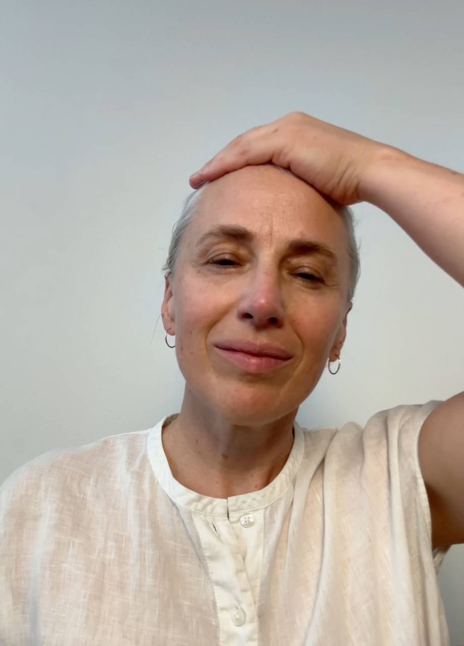 A woman in a headscarf sips from a cup.