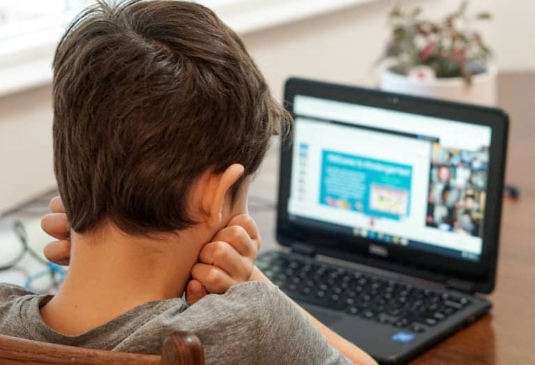 boy in gray shirt using black laptop computer
