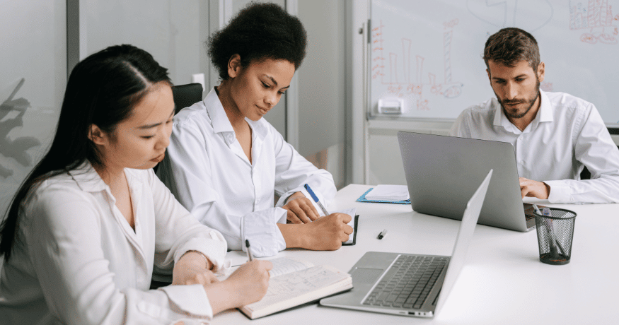 two women one man working white desk