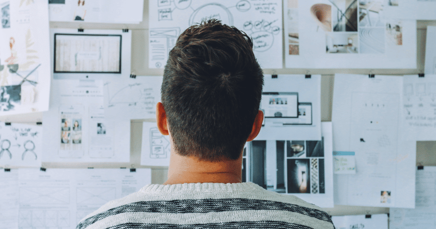 man looking at papers on wall