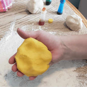 hand holding homemade yellow play dough