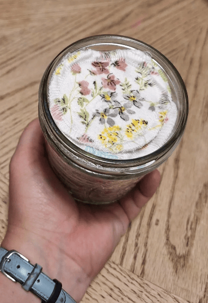 hand holding a jar of reusable cotton rounds with floral print
