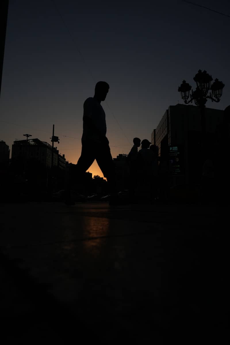 A silhouette of a person walks at dusk.