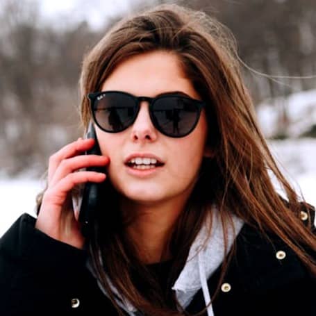 A woman walking in the snow talking on a cell phone